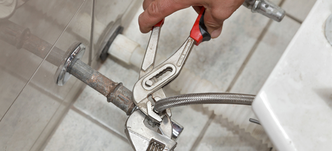Plumbing repair: a wrench working on bathroom pipework